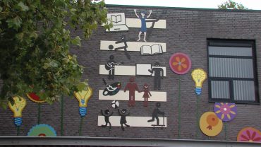 De oud-directeur van De Bloemaert en de cultuurcoördinator wilden graag zichtbaar maken waar die school voor staat. Toen hebben ze stichting BIK Collectief gevraagd om een wandkunstwerk te ontwerpen en te maken.