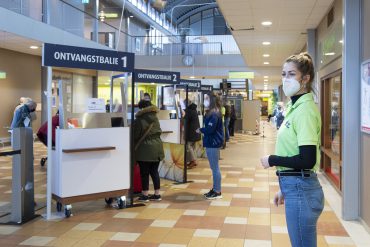 Stewards wijzen iedereen bij de nieuwe ontvangstbalies van het ETZ op de beschermingsmaatregelen en ontvangen de patiënten en bezoekers.