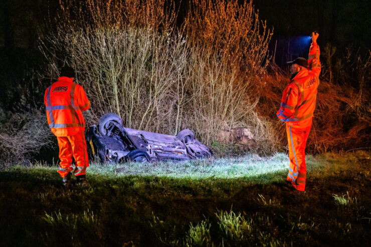 Auto ondersteboven in de sloot met ambulancepersoneel eromheen